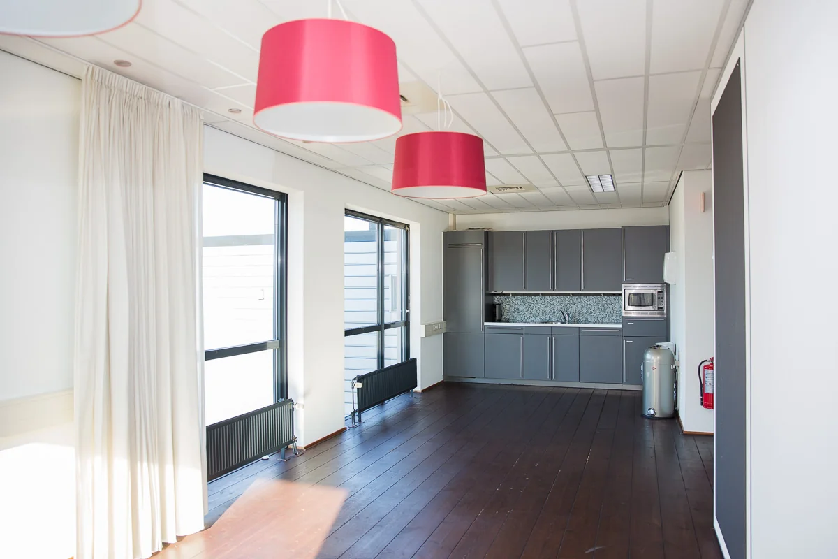 Moderne keukenruimte met grijze kasten, grote ramen en hanglampen aan de Laan van ’s-Gravenmade.